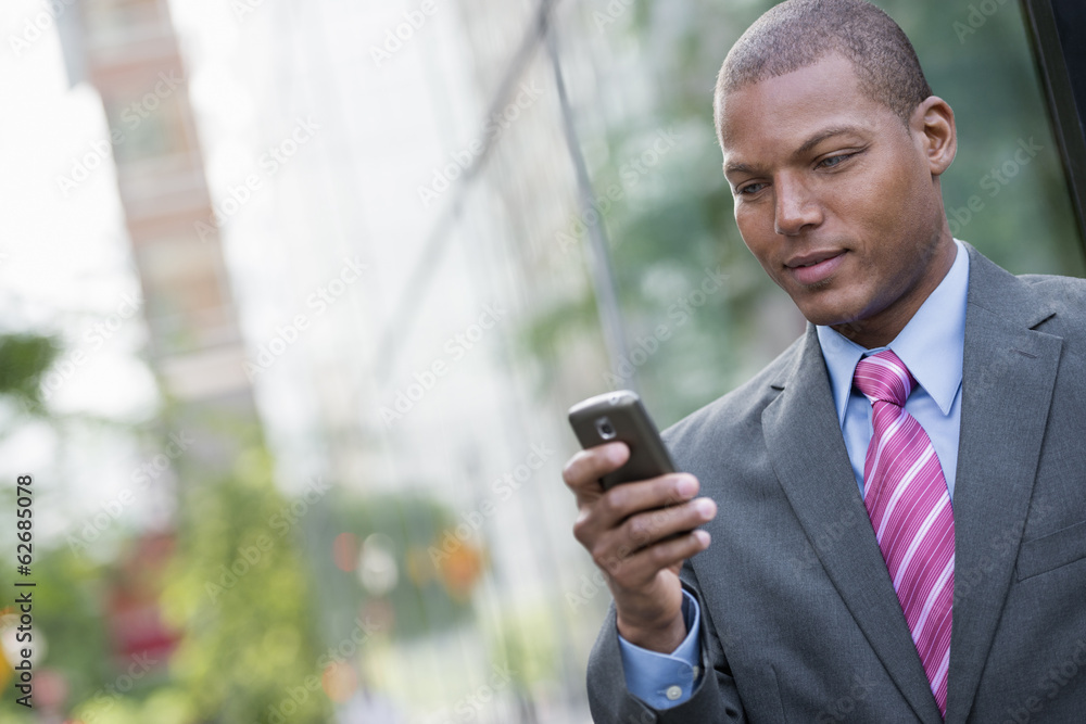 A Young Man In A Business Suit With A Blue Shirt And Red Tie. On A New York City Street. Using A Smart Phone. 