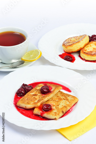 Food of Crepes, cheesecakes with berry sause and cup of tee.