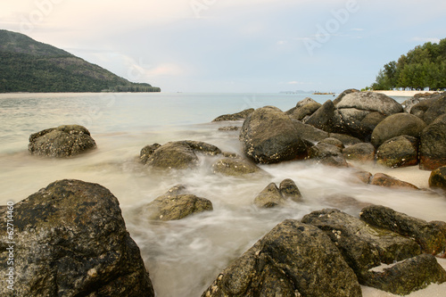 beach with rocks and waves; sunset background
