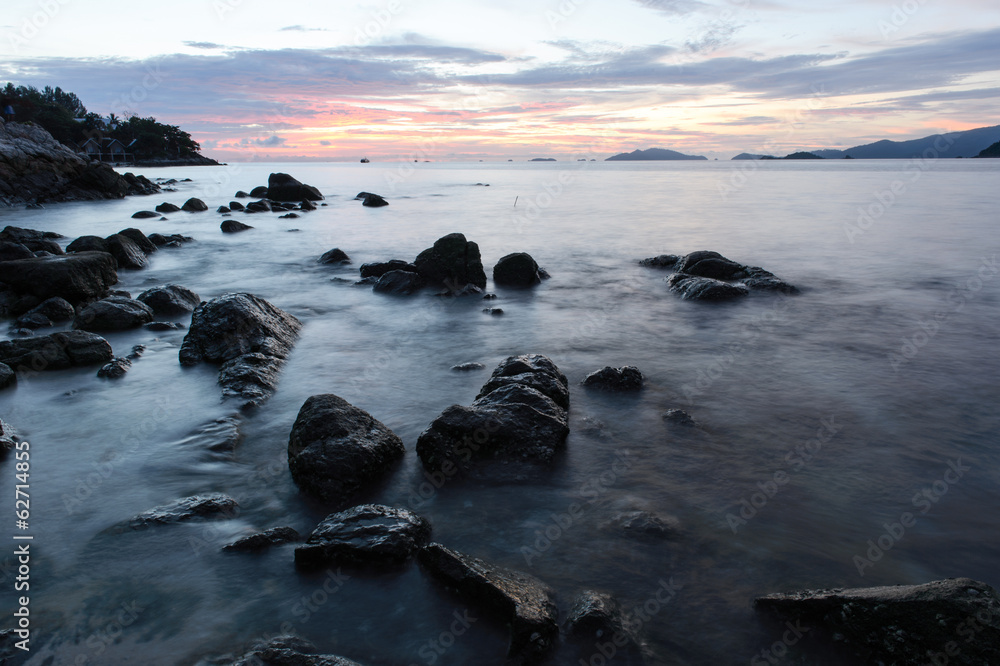 Obraz premium beach with rocks and waves; sunset background