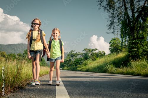 two girls with backpacks walking on the road