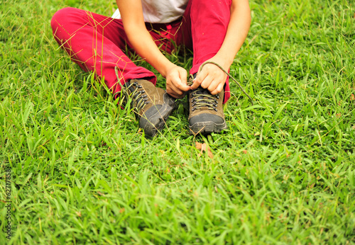 hiker tying shoelace on grass © lzf
