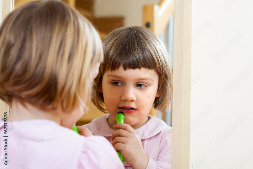 little girl front of  mirror with cosmetic