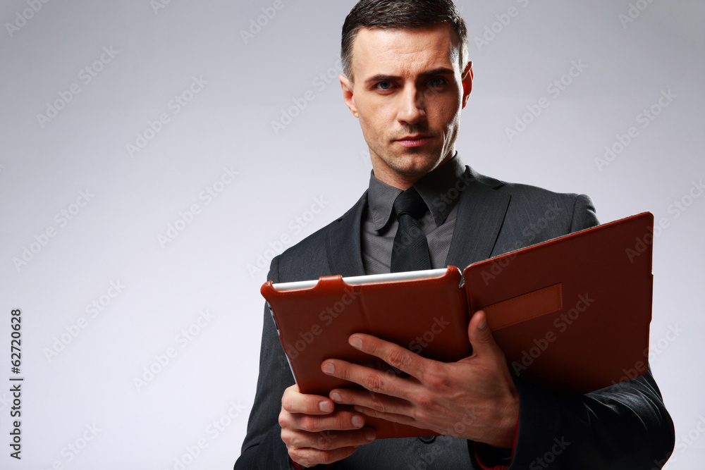 Smart businessman holding tablet computer over gray background Smart businessman holding tablet computer over gray background