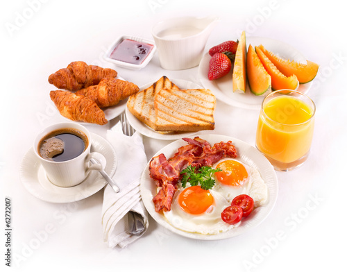 Breakfast with fried eggs, coffee,  juice, croissant and fruits