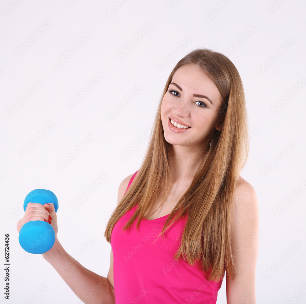 Young beautiful fitness girl exercising with dumbbells in gym Young beautiful fitness girl exercising with dumbbells in gym
