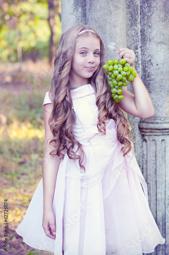 Beautiful girl in the garden with a bunch of grapes