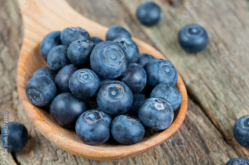 fresh blueberries in a wooden spoon over wooden table