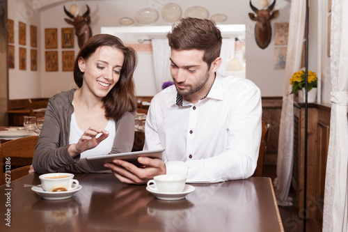 Young woman and man using tablet in coffee shop