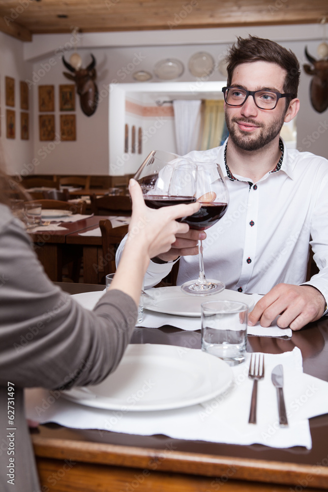 Smiling young man clinking glasses with his girlfriend Smiling young man clinking glasses with his girlfriend