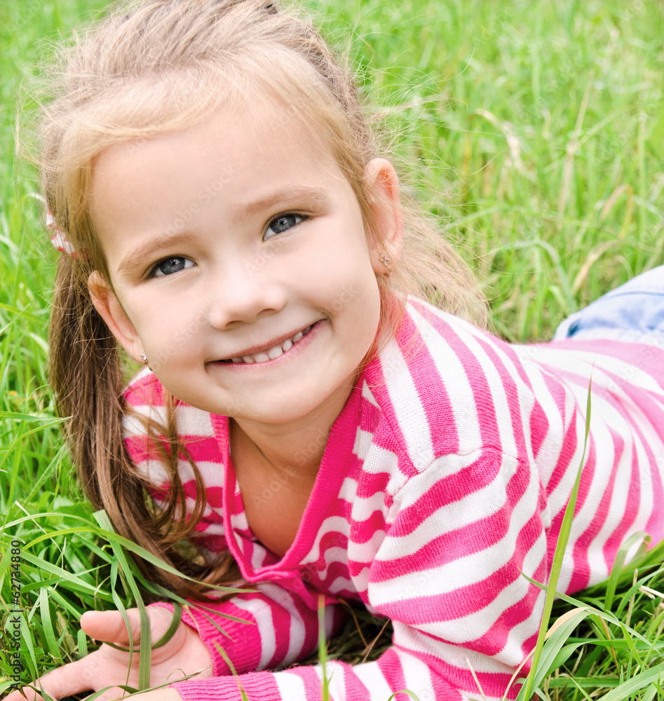 Portrait of adorable smiling little girl lying on grass Portrait of adorable smiling little girl lying on grass