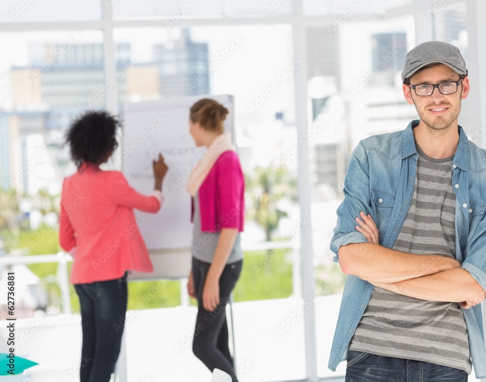 Casual male artist with colleagues in background at office Casual male artist with colleagues in background at office