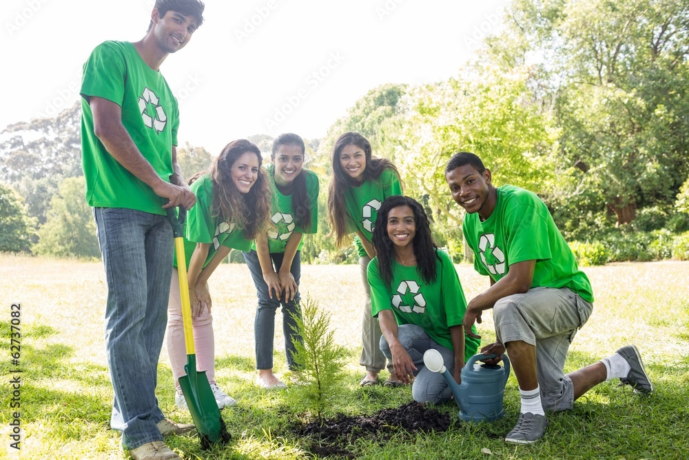 ”Men and women planting a tree and enjoying their work.”