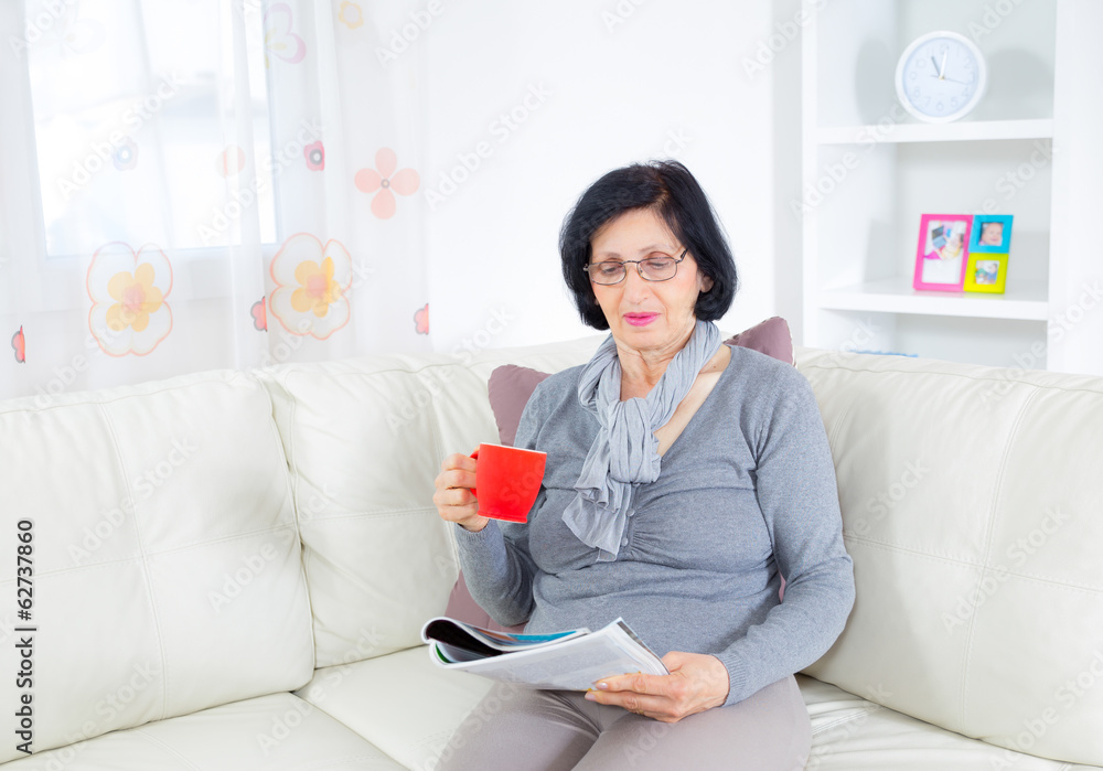 Grandmother enjoying a rest, reading magazine and drinking coffe Grandmother enjoying a rest, reading magazine and drinking coffe