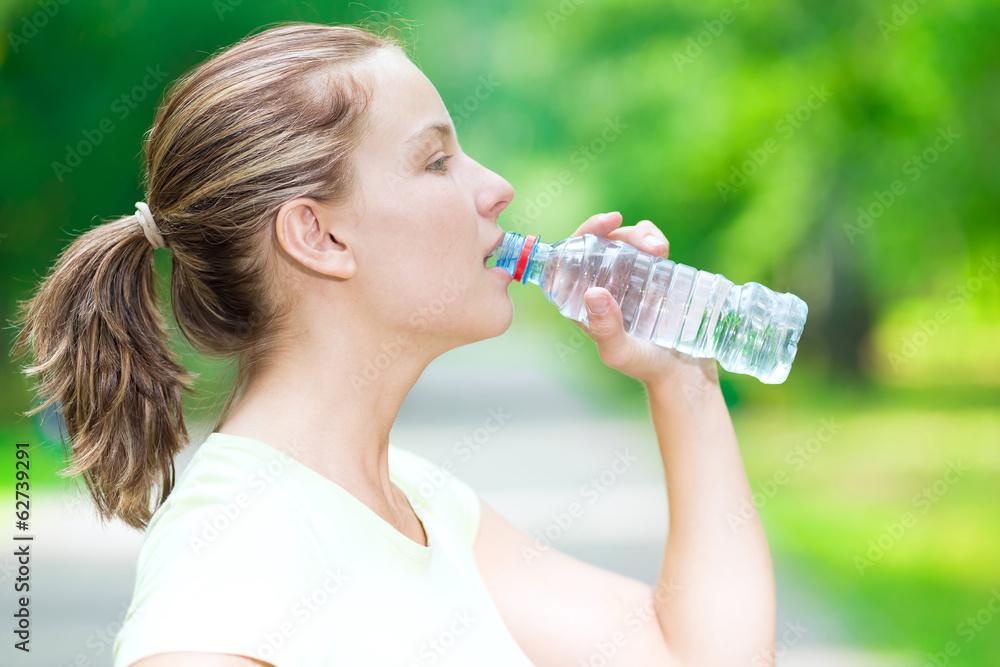 Woman drinking cold mineral water from a bottle after fitness ex Woman drinking cold mineral water from a bottle after fitness ex