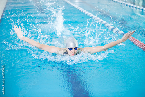 Young girl in goggles swimming butterfly stroke style