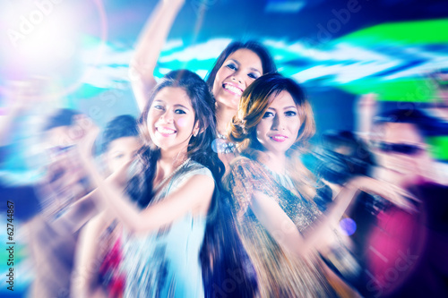 Asian girls partying on dance floor of disco nightclub