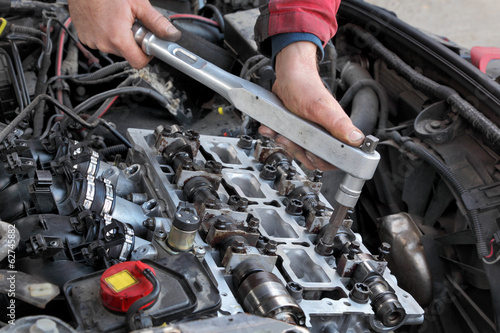 Mechanic fixing cylinder head with camshaft using socket wrench