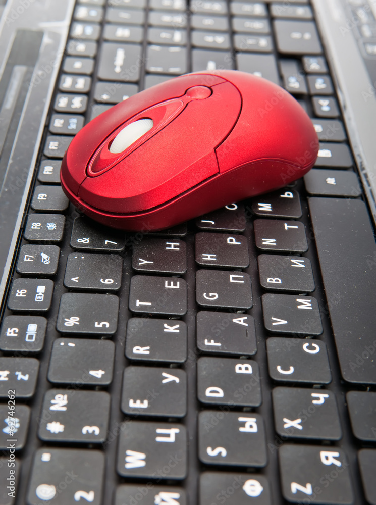 The red computer mouse on the black keyboard.. The red computer mouse on the black keyboard..