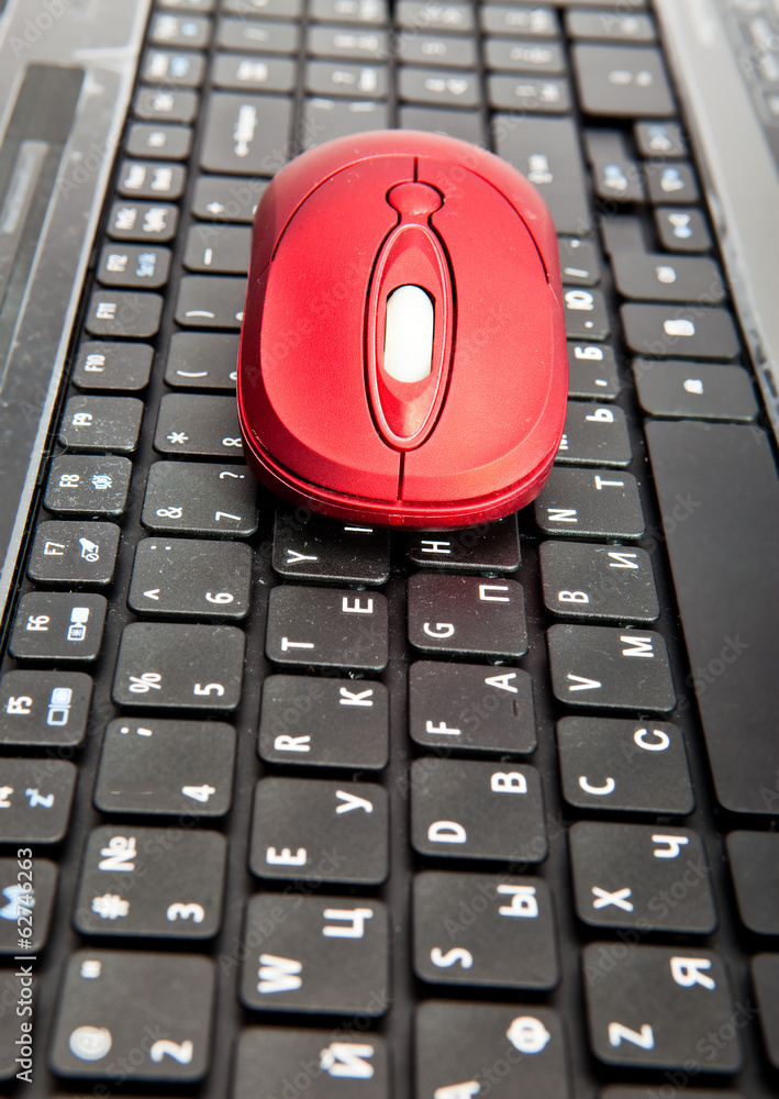 The red computer mouse on the black keyboard.. The red computer mouse on the black keyboard..