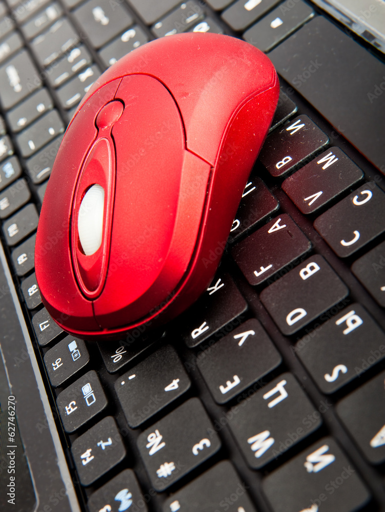 The red computer mouse on the black keyboard.. The red computer mouse on the black keyboard..