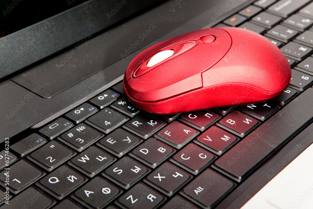 The red computer mouse on the black keyboard.. The red computer mouse on the black keyboard..