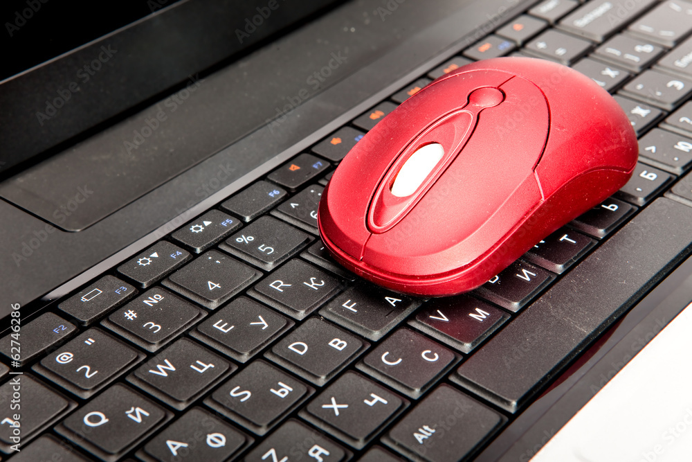 The red computer mouse on the black keyboard.. The red computer mouse on the black keyboard..