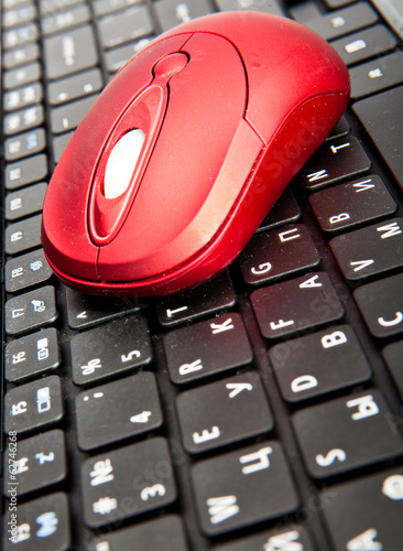 The red computer mouse on the black keyboard..