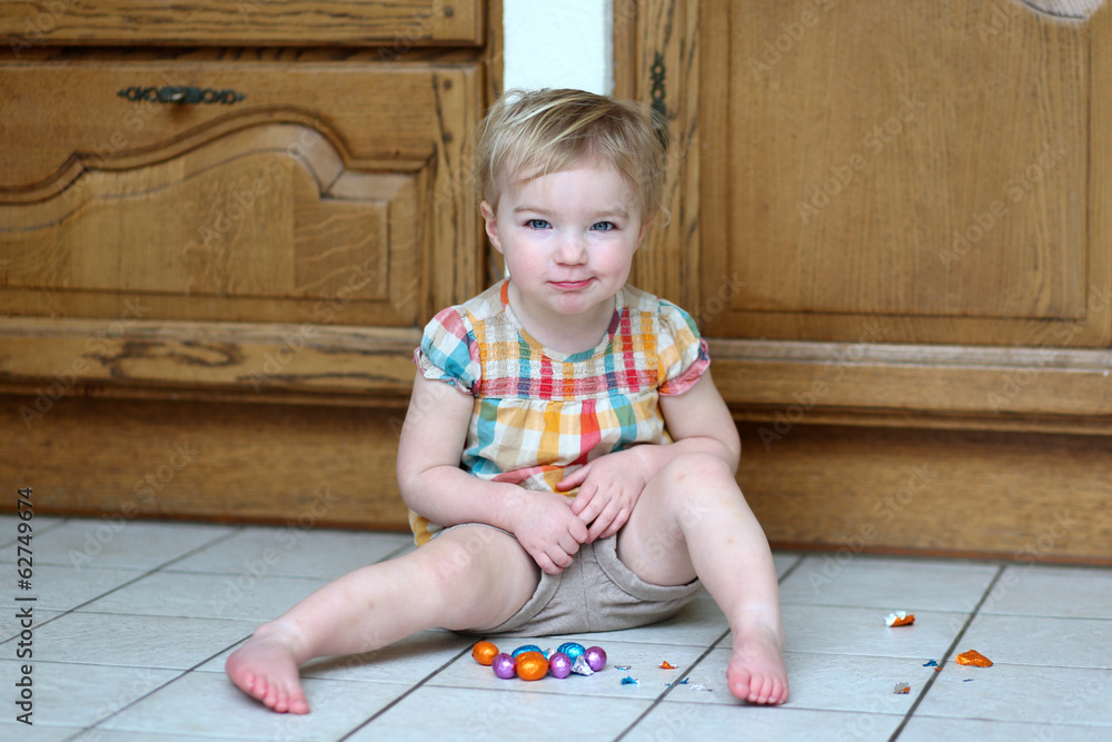 Funny toddler girl eating delicious Easter chocolate eggs Funny toddler girl eating delicious Easter chocolate eggs