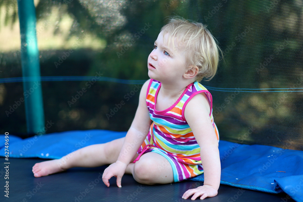 toddler girl in colorful rainbow dress relaxing on trampoline toddler girl in colorful rainbow dress relaxing on trampoline