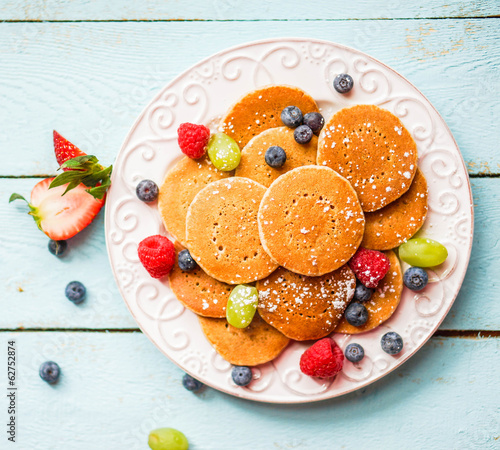 Pancakes with berries on wooden background