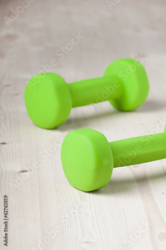 small green dumbbells on wooden surface