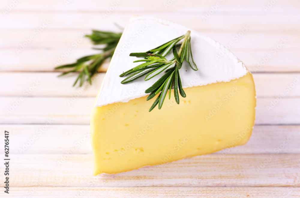 Tasty Camembert cheese with rosemary, on wooden table Tasty Camembert cheese with rosemary, on wooden table