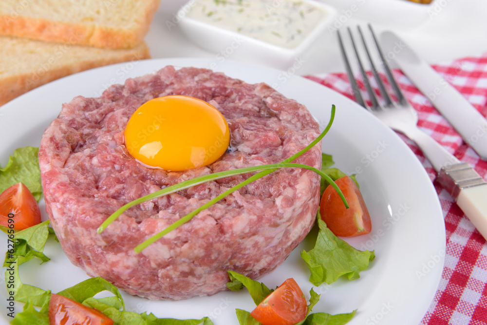 Delicious steak tartare with yolk on plate on table close-up Delicious steak tartare with yolk on plate on table close-up