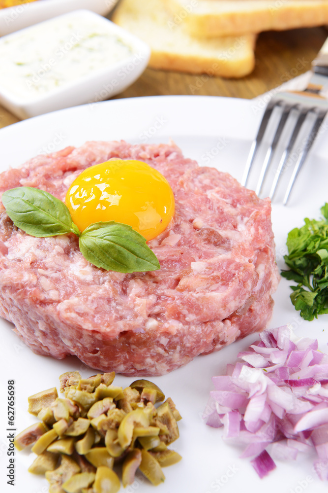 Delicious steak tartare with yolk on plate on table close-up