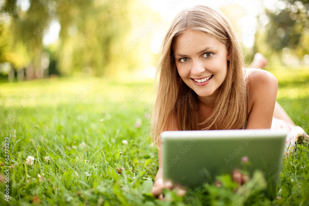Young woman with digital tablet laying on grass Young woman with digital tablet laying on grass