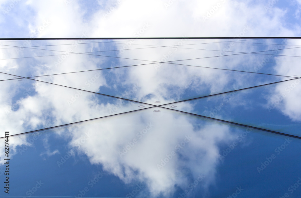 reflexions of clouds and blue sky in facade of modern building