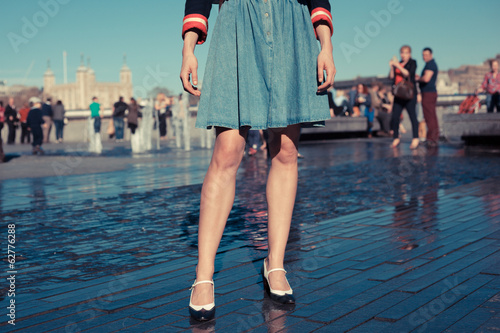 Young woman standing by fountain in city on a hot day photo