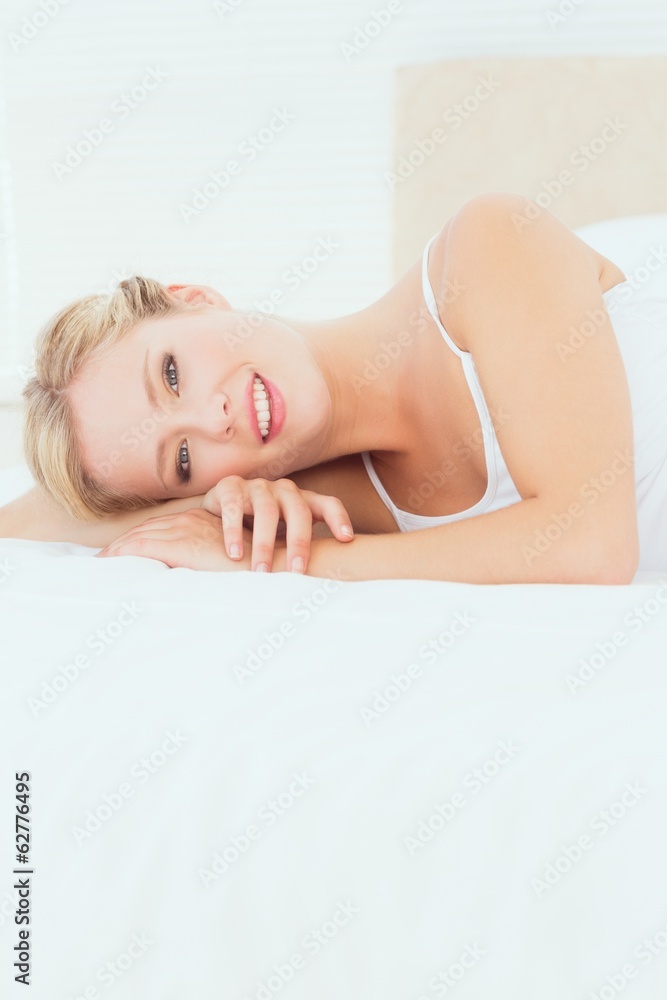 Pretty young blonde lying on her bed smiling at camera Pretty young blonde lying on her bed smiling at camera