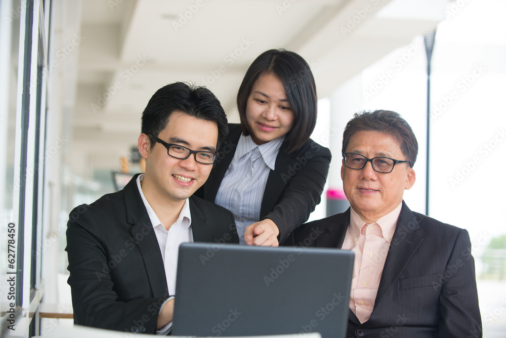Group of asian business people gathered together at a table dis Group of asian business people gathered together at a table dis