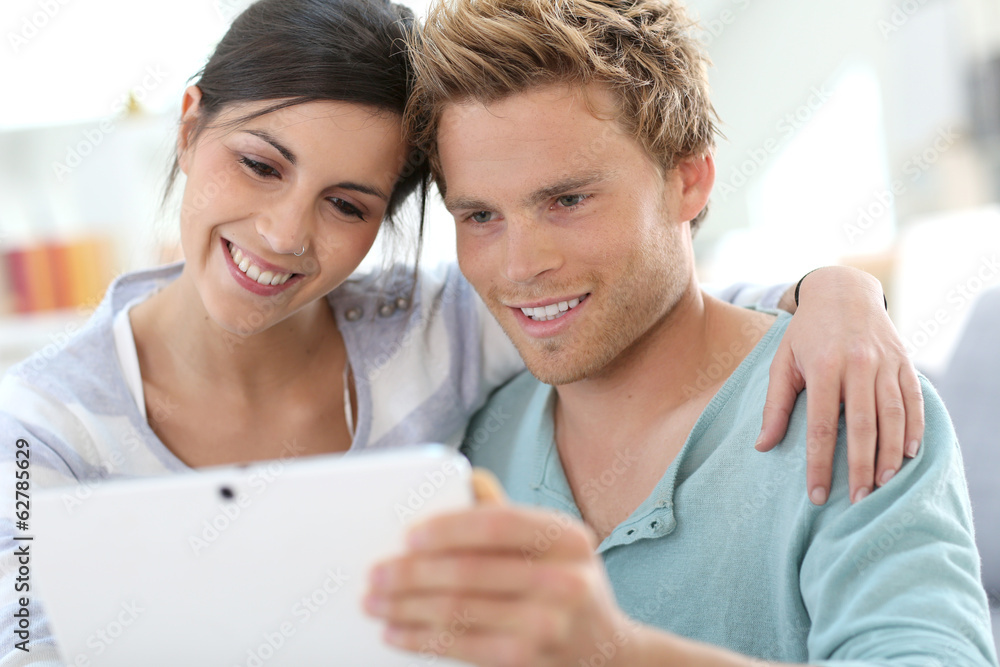 Young couple in sofa websurfing on internet with tablet Young couple in sofa websurfing on internet with tablet