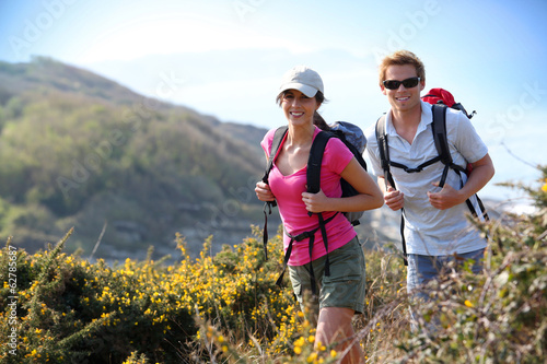 Couple of hikers in country field by the ocean