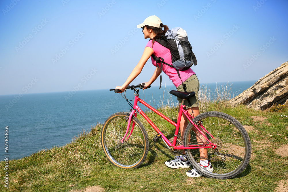 Young woman riding bike by ocean coast