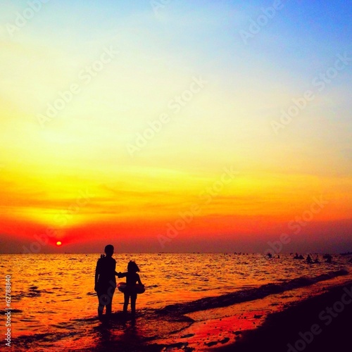 Silhouette of mother and daughter at sunset sea