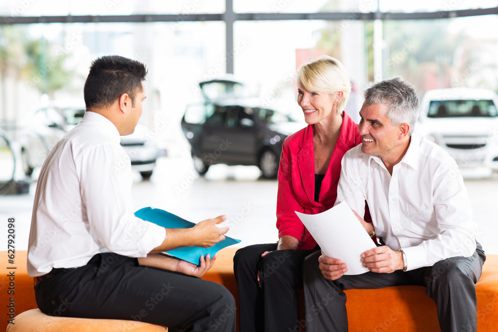 Obraz premium vehicle salesman explaining contract to senior couple