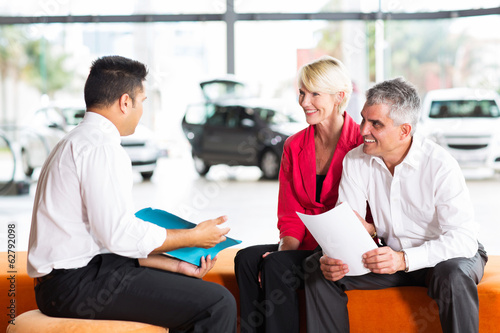 vehicle salesman explaining contract to senior couple