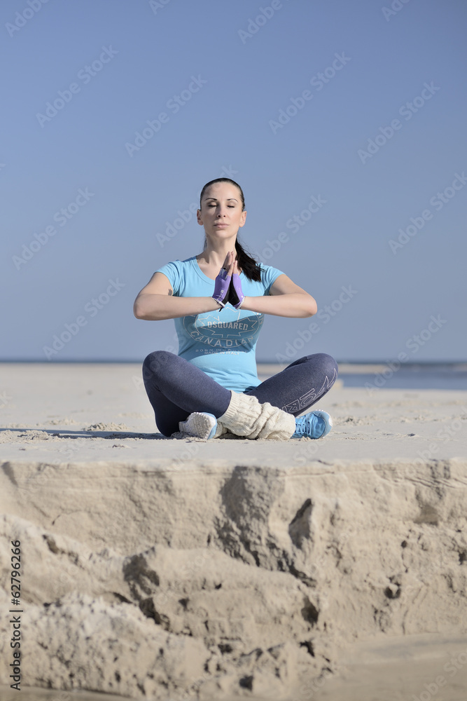 young woman meditating on the beach