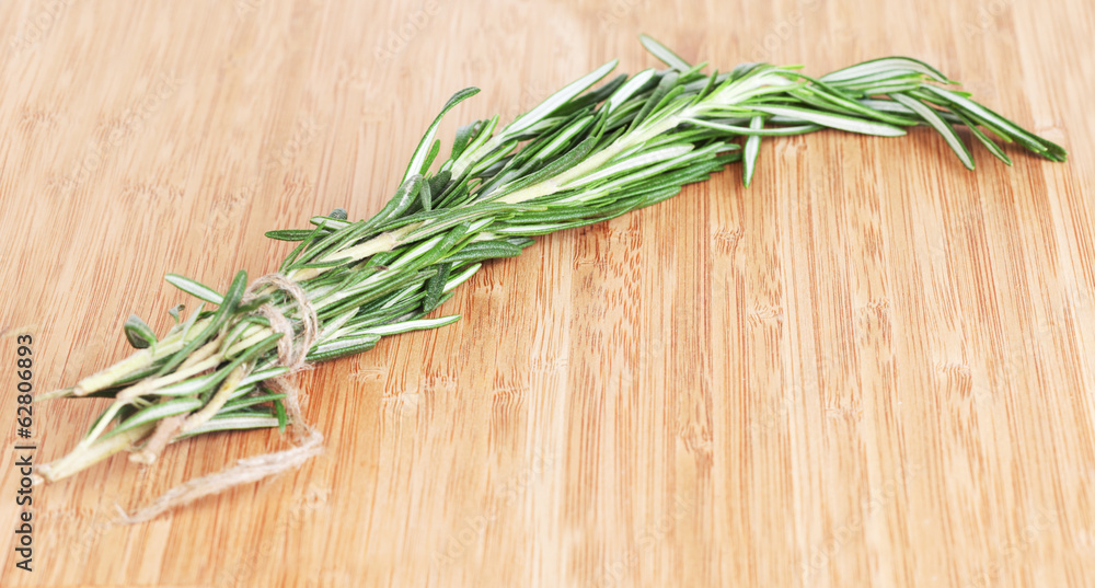 Rosemary branch on a chopping wooden board Rosemary branch on a chopping wooden board