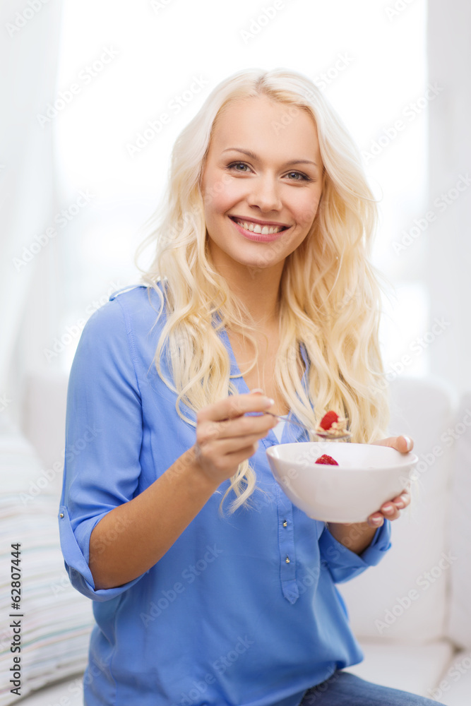smiling woman with bowl of muesli having breakfast