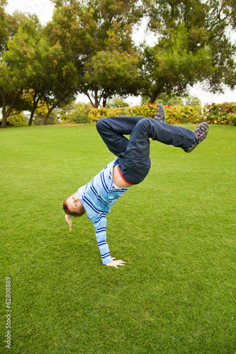 Child playing on green grass in a park jumping